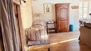 A rustic room with a wooden ceiling, a bed with a striped blanket, a wooden cabinet, and a window with natural light.