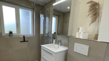Une salle de bain moderne équipée de toilettes, d’un lavabo et d’une douche.