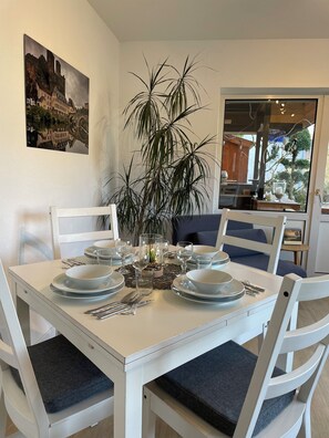 A dining table set with plates, bowls, and cutlery, surrounded by chairs with cushions. - Nice apartment in the heart of the Taunus and yet close to the city (Waldems)