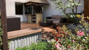 Un patio couvert aménagé avec des sièges, un petit coin bar et des plantes en pot.