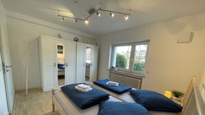 Une chambre avec un grand lit, une armoire et une fenêtre donnant sur des arbres.