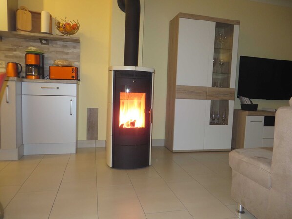 A living room with a wood-burning stove, a television, and a cabinet with glass doors.