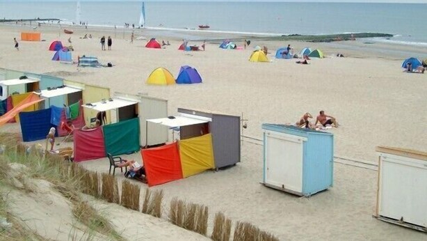 A beach with colorful tents and small buildings, likely for accommodation or services.