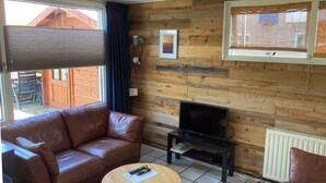 A cozy living room with a brown leather sofa, a small wooden coffee table, and a television on a black stand.