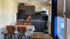 A compact kitchen with dark cabinets, a microwave, and a clock on the wall.