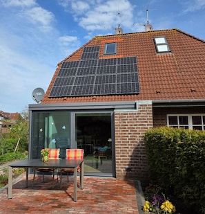Una casa con paneles solares, puerta de vidrio y fachada de ladrillo.