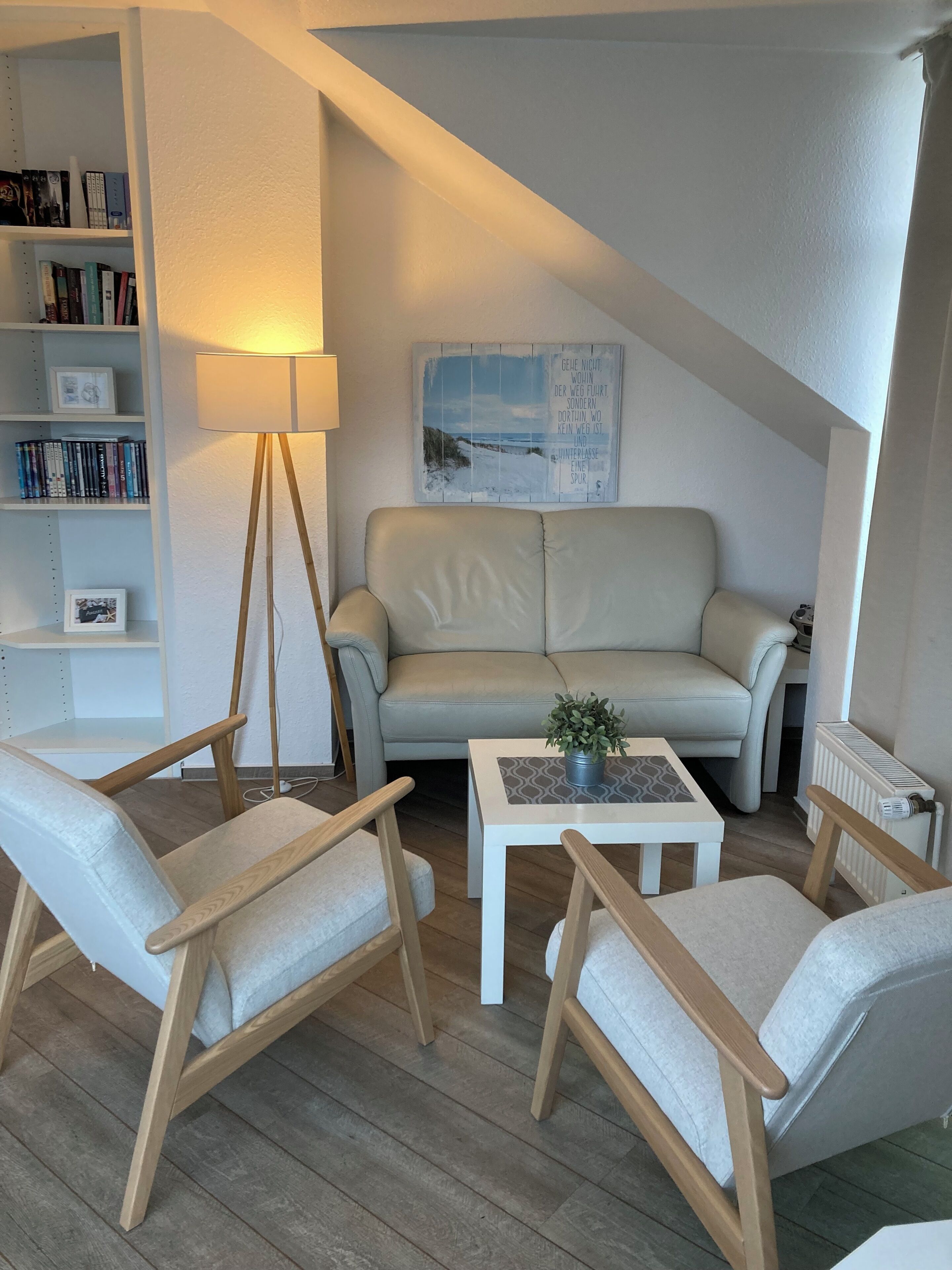 Un salon confortable avec un canapé, deux fauteuils, une table basse et un lampadaire.