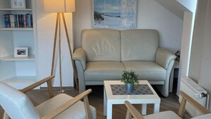 Ett mysigt vardagsrum med en soffa, två fåtöljer, ett soffbord och en golvlampa.