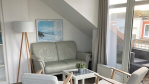 Ett modernt vardagsrum med en soffa, två fåtöljer, ett soffbord och en golvlampa.