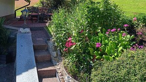 A garden with a red umbrella, steps leading to a building, and a statue of a cat. - Beautiful, large, comfortable vacation apartment to feel at home in. (Dachsberg (Südschwarzwald))