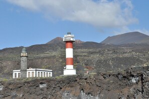 Un faro con una torre a rayas rojas y blancas, una torre más pequeña y un edificio con cúpula.