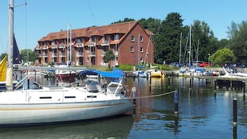 Eine Marina mit vertäuten Booten, ein Backsteinhaus mit Balkonen und ein klarer Himmel.