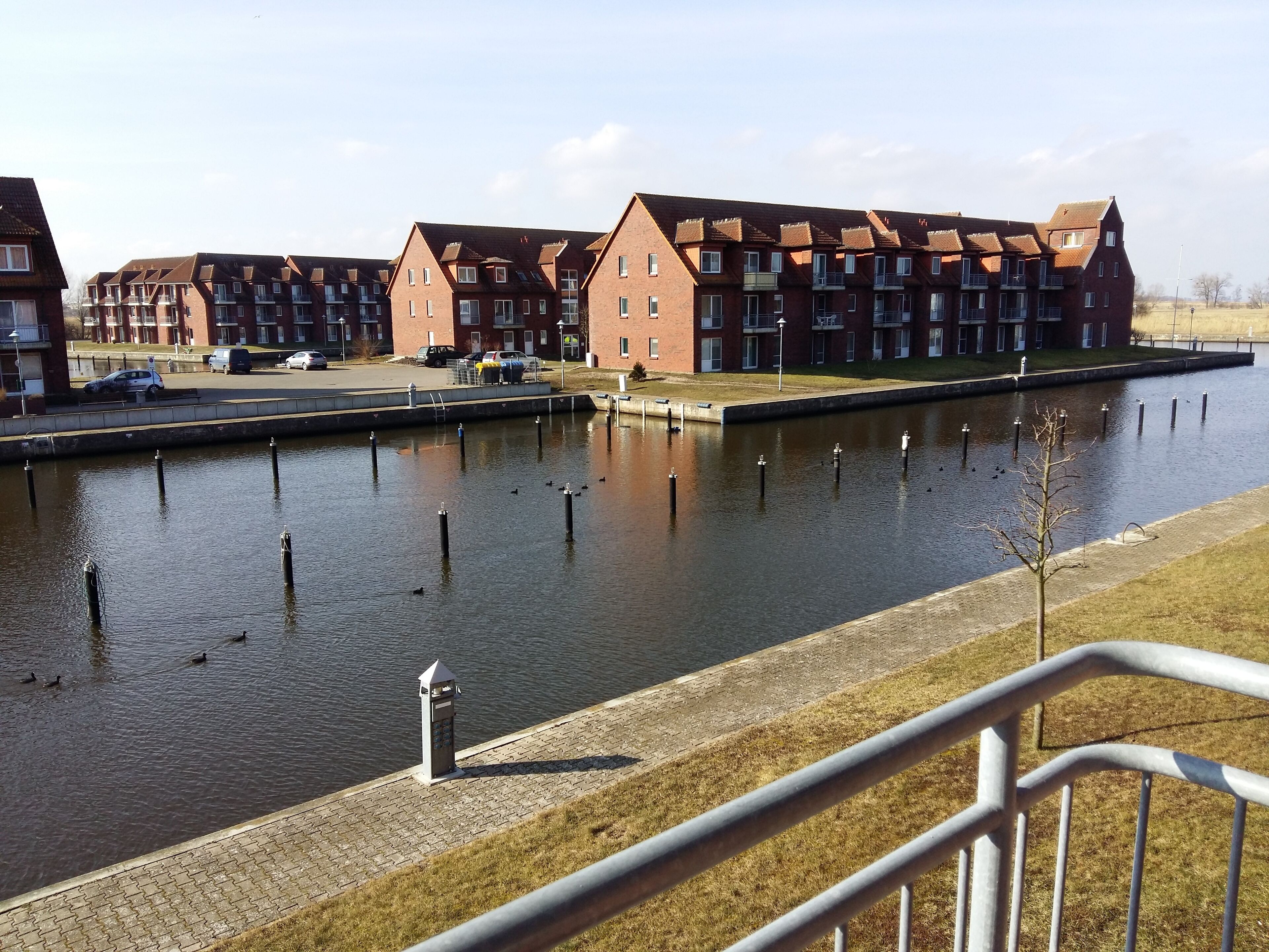 Un canal bordé d’une rangée d’immeubles en briques, d’une promenade pavée et d’une rambarde en métal.