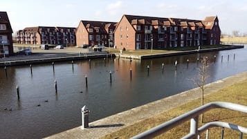 Un canal bordé d’une rangée d’immeubles en briques, d’une promenade pavée et d’une rambarde en métal.