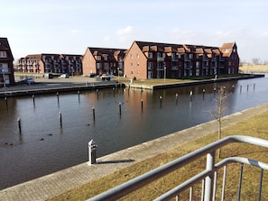 Ein Kanal mit einer Reihe aus Ziegelgebäuden, einem gepflasterten Weg und einem Metallgeländer.