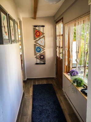 A hallway with a black carpet, a wooden door, and a window with curtains.