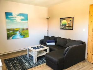 A living room with a dark-colored sofa, a small wooden coffee table, and two paintings on the wall. - Ferienwohnung Nr. 2-Apartment-Private Bathroom (Schwabstedt)
