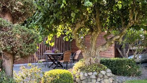 Un jardín con una mesa y sillas, un muro de piedra y una estatua.