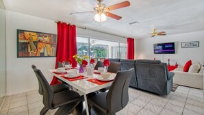 A dining area with a table set for four, two ceiling fans, a painting, and a TV on the wall. - Holiday home with large heated pool - south exposure (Cape Coral)