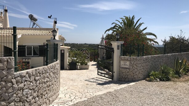 A gated entrance with a stone wall, a metal gate, and a sign reading "CASA DOS LOBOS". - Detached villa with sea view, heated pool and air conditioning (Caramujeira)