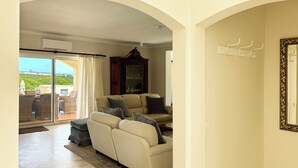A living room with a sofa, a cabinet, and a view of the outdoors. - Detached villa with sea view, heated pool and air conditioning (Caramujeira)