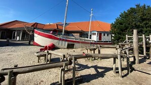 Un bateau était amarré sur une plage de sable, avec un bâtiment visible au loin.