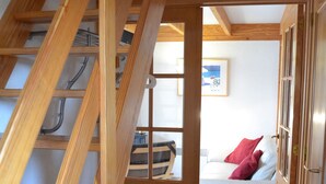 A wooden staircase leading to a bedroom with a white bed and a red pillow. - Directly behind the dunes in the Fabiola Beach Park (Wenduine)