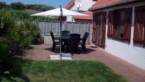 A patio with a table and chairs, a satellite dish, and a red-tiled roof. - Directly behind the dunes in the Fabiola Beach Park (Wenduine)