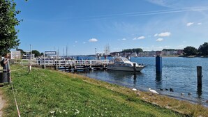 Ein Yachthafen mit vertäuten Booten, einer Rasenfläche und blauem Himmel.