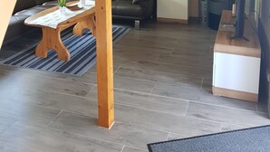 Ein großzügiger Wohnbereich mit einer Holztreppe, einem schwarzen Ledersofa, einem Couchtisch aus Holz und einem Kamin.