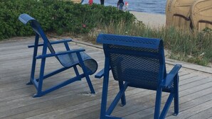 To blå metalstole på en træterrasse ud til stranden.