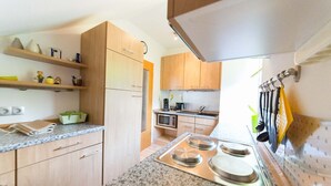 A kitchen with wooden cabinets, granite countertops, a stove, and a microwave. - Relaxation in the vineyards - Ferienwohnung Isinger (Rüdesheim am Rhein)