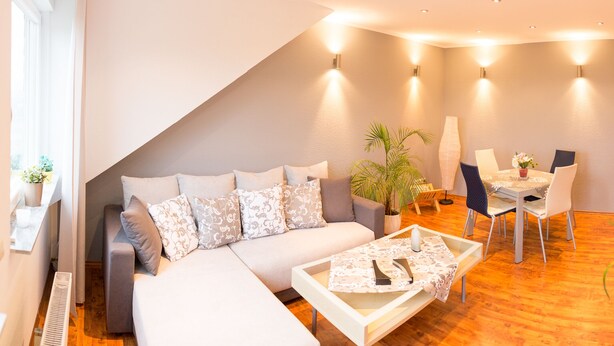 A modern living room with a sofa, coffee table, and dining table. - Relaxation in the vineyards - Ferienwohnung Isinger (Rüdesheim am Rhein)