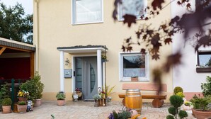 A courtyard with potted plants, a wooden bench, and a wheelbarrow. - Relaxation in the vineyards - Ferienwohnung Isinger (Rüdesheim am Rhein)