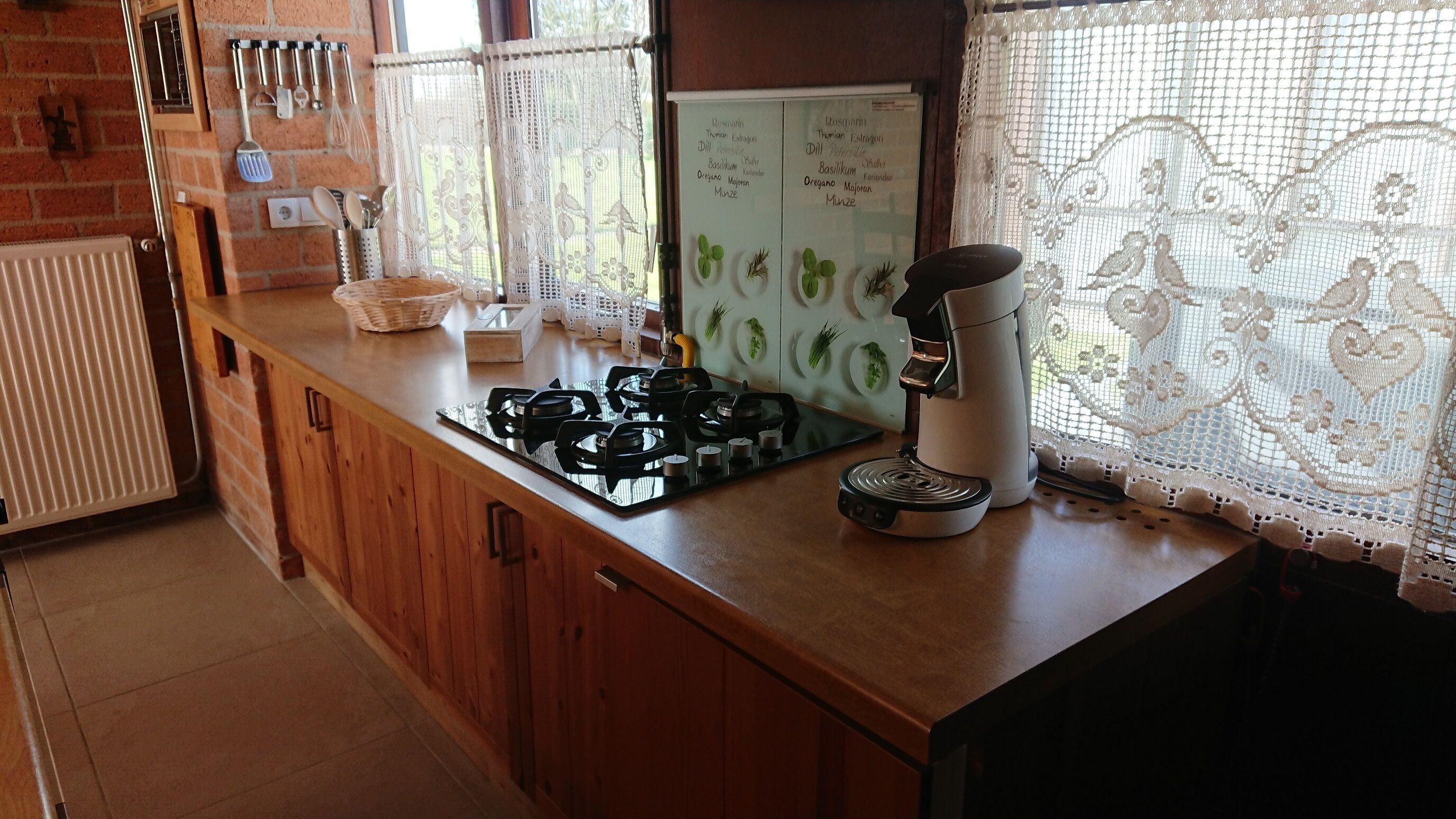 A kitchen with a gas stove, a coffee maker, and a whiteboard with green plants.