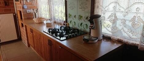 A kitchen with a gas stove, a coffee maker, and a whiteboard with green plants.