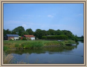 En stilla flod med en liten båt, hus längs flodstranden och frodig grönska.