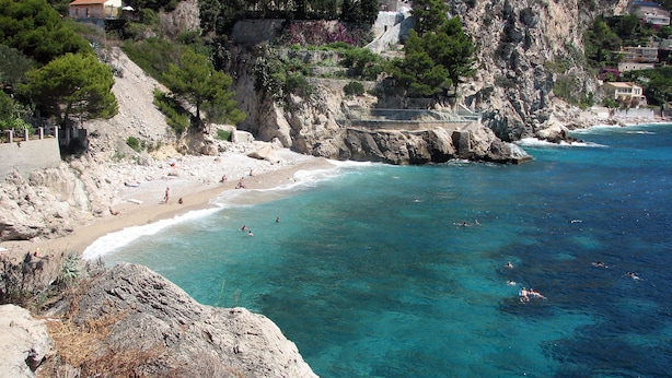 Zona costera con playa, acantilados rocosos y edificios.