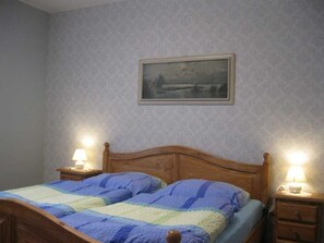 Ein Schlafzimmer mit einem hölzernen Bett, zwei Nachttischlampen und einem gerahmten Bild an der Wand.