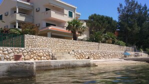 Un edificio de dos plantas con un muro de contención de piedra y una piscina al frente.