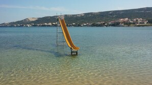 Vista despejada de una playa con un tobogán amarillo que llega al agua.