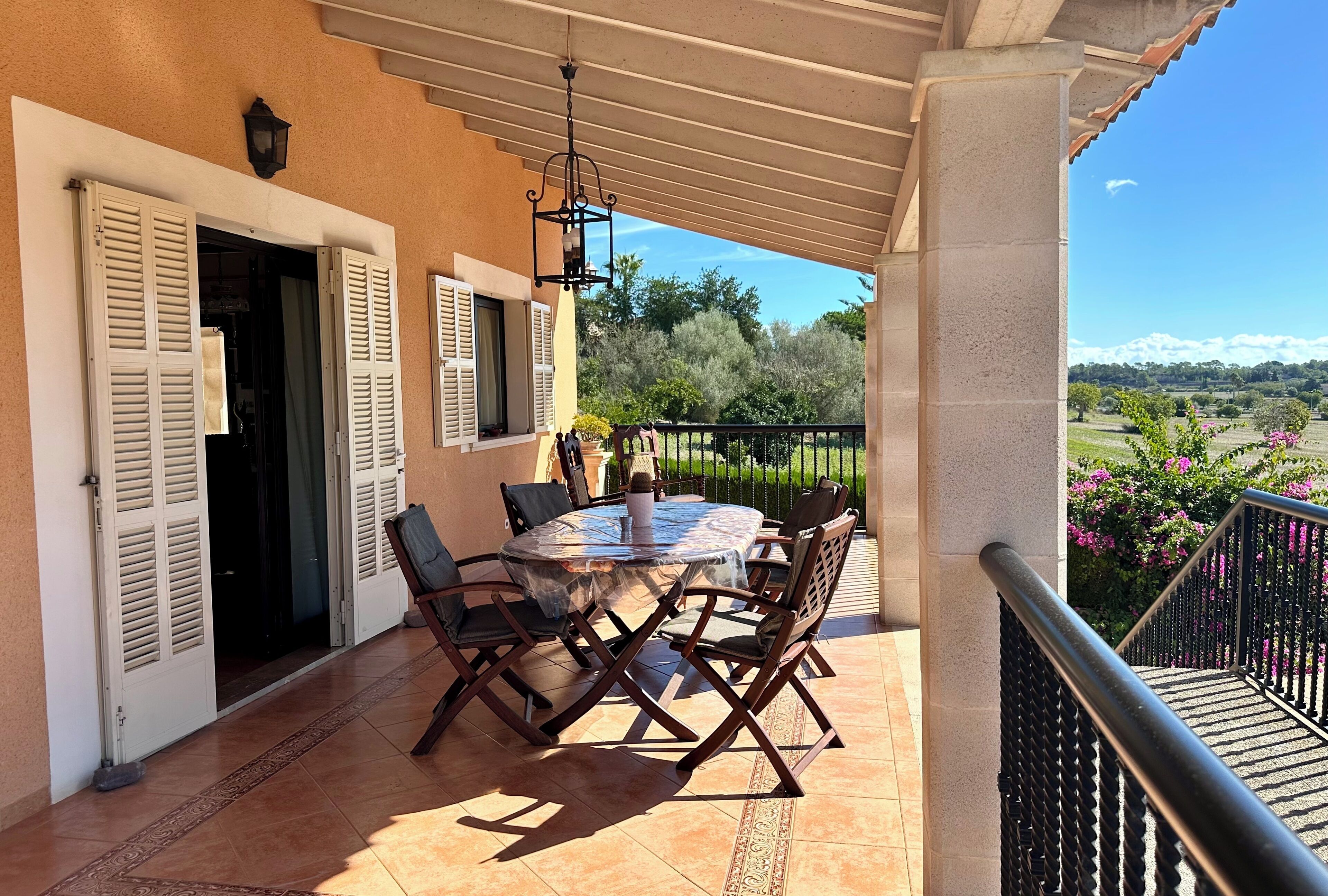 Un patio exterior con una mesa y sillas redondas, una pérgola y vistas del paisaje.