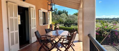 Un patio exterior con una mesa y sillas redondas, una pérgola y vistas del paisaje.