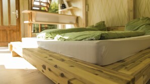 A wooden bed with a mattress and green bedding in a room with wooden walls and shelves. - Apartment Casa Casimir with Elbe view balcony & large garden (for soccer/volleyball) (Dresden)