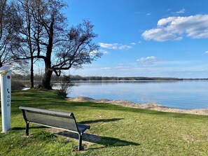 Eine Bank am See unter einem klaren Himmel.