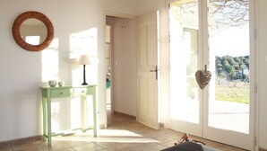A room with a green console table, a round mirror, and a sliding glass door leading to an outdoor area.