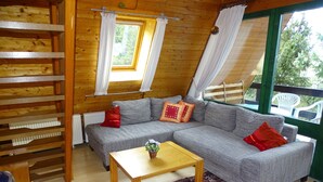 A cozy wooden cabin interior with a sofa, a small table, and a patterned rug. - Ideal nature: sunny home between a swimming lake, forest & the Altmühl River (Bayern)