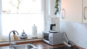 Een keuken met een spoelbak, fornuis, magnetron en koffiezetapparaat.