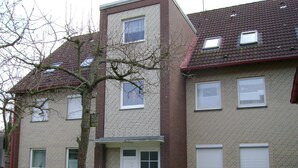 Een woonhuis met twee verdiepingen, een bakstenen gevel, meerdere ramen en een klein portaal.