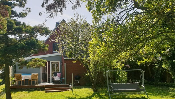 A backyard with a wooden deck, a swing set, and a barbecue grill. - To get my head clear! Cozy cottage in Ditzum, large garden, dogs ok! (Ditzum)